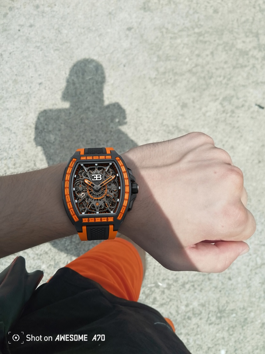 Montre squelette noire et orange portée au poignet sous la lumière du jour